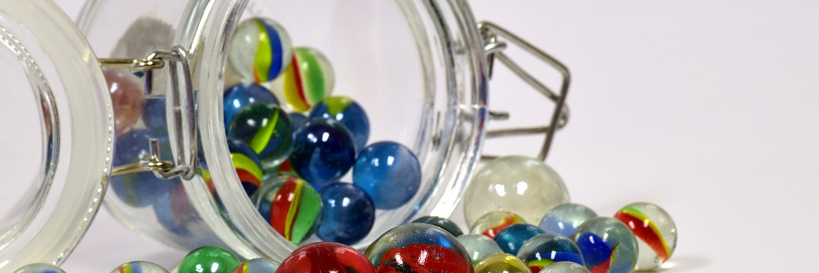 Multi-colored marbles spilling out of jar